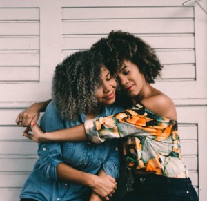 Two black women hug each other. 