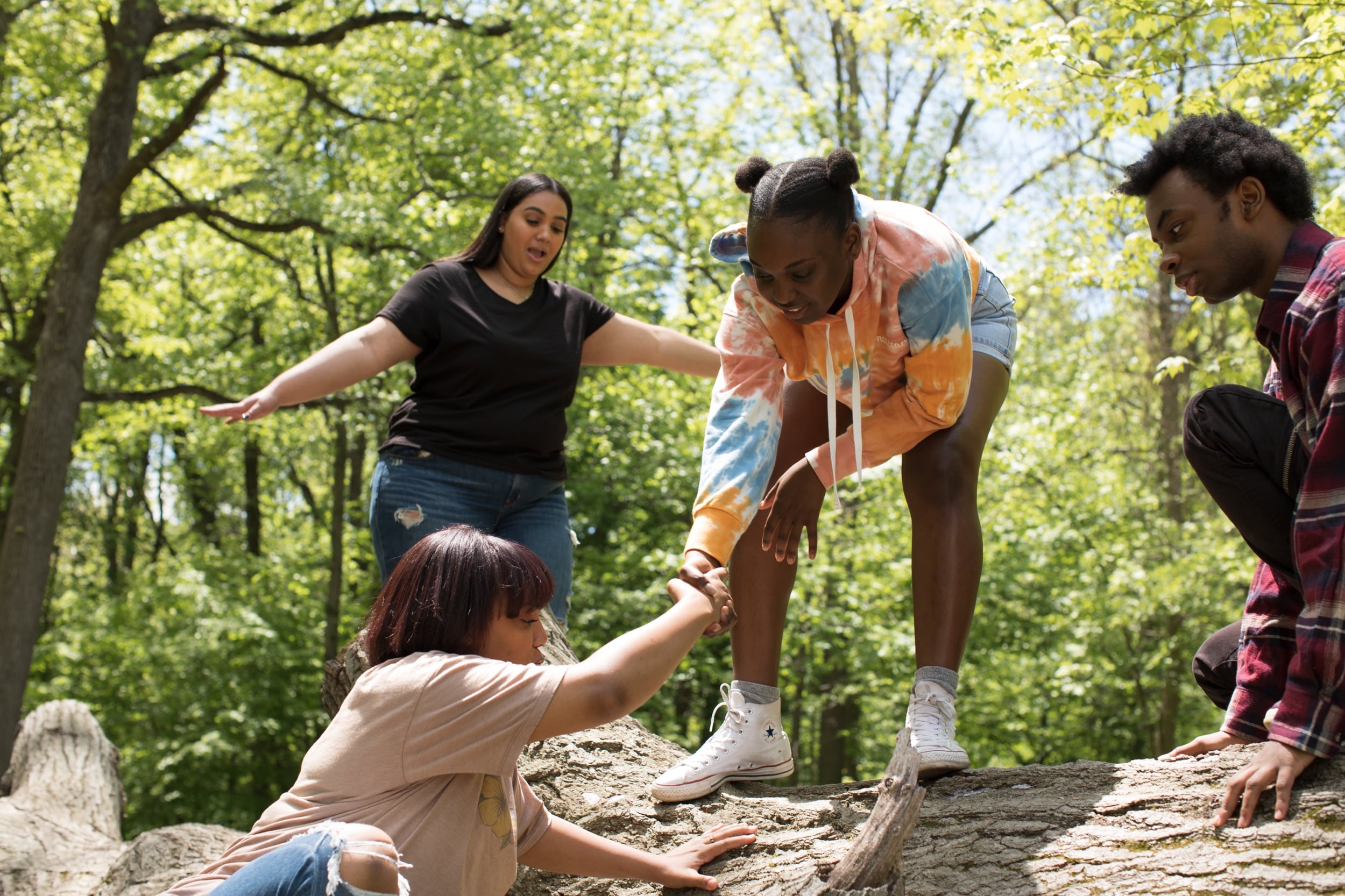A group of BIPOC youth hiking together through a forest.