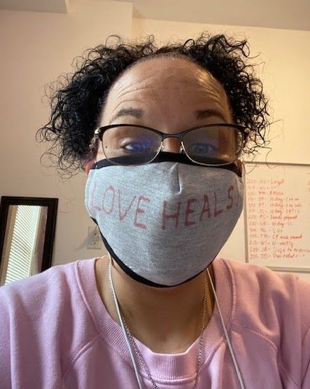 Denise Riggins, senior general manager of two DISH buildings that welcome formerly homeless tenants during COVID-19, is seen wearing a mask that reads, "Love heals."
