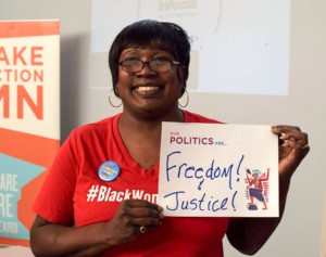Cherise Payton is shown holding up a sign that reads, "Our politics are Freedom & Justice!" at TakeAction Minnesota’s annual member meeting in Duluth, Winter 2019.