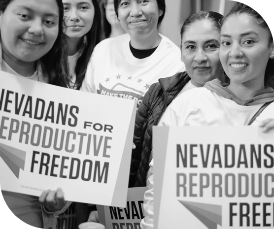 Five women smiling and holding placards that read “Nevadans for Reproductive Freedom,” showing unity and public support for abortion access in Nevada.