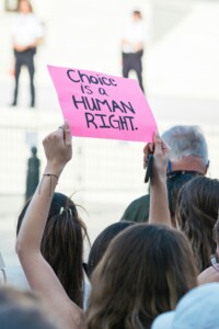 Woman holding a 'Choice is a Human Right' sign at a protest. 