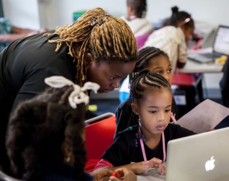 A Black teacher instructing young Black students on computers. Photo credit: General Assembly, a corporate partner with Tides