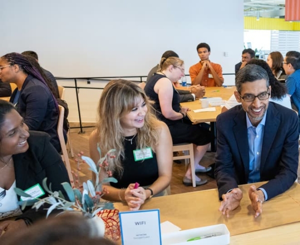 Groups of people sitting at tables talking with each other during a Google Cybersecurity event.