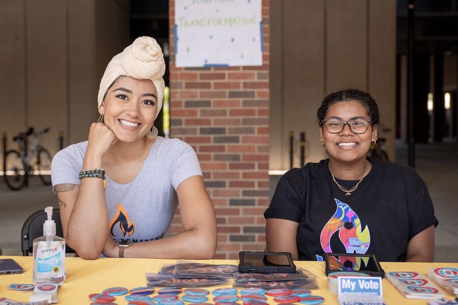 Two young women of color organizers tabling with Leaders Igniting Transformation, a Tides Healthy Democracy Fund grantee.