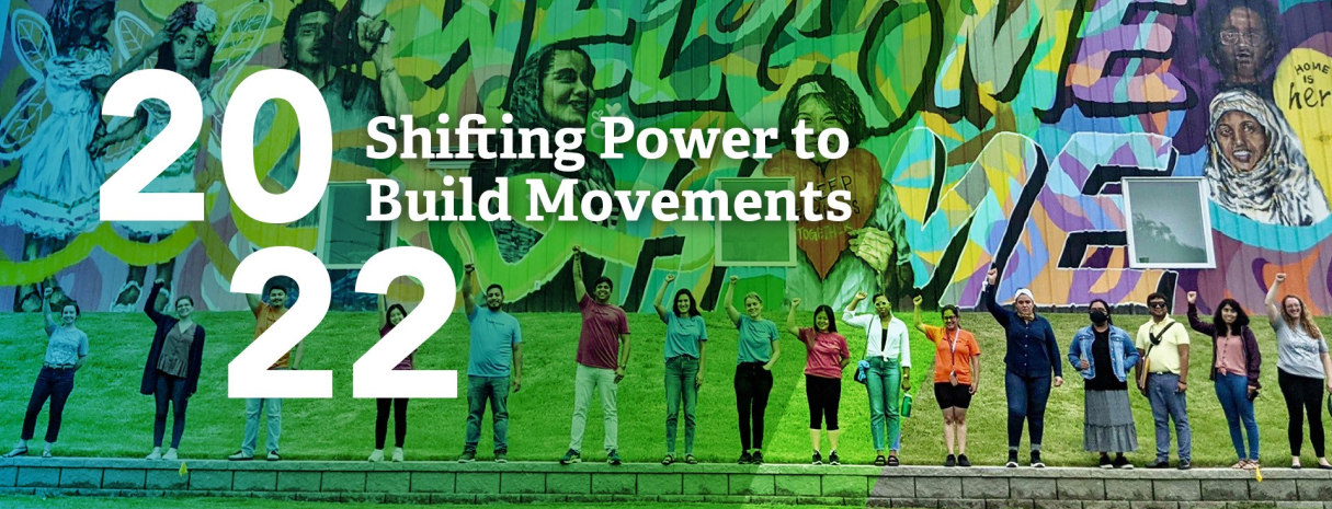 The words ‘2022 Shifting Power to Build Movements’ laid over an image of a group of people fro Tennessee Immigrant and Refugee Rights, a Tides I-Belong grantee.
