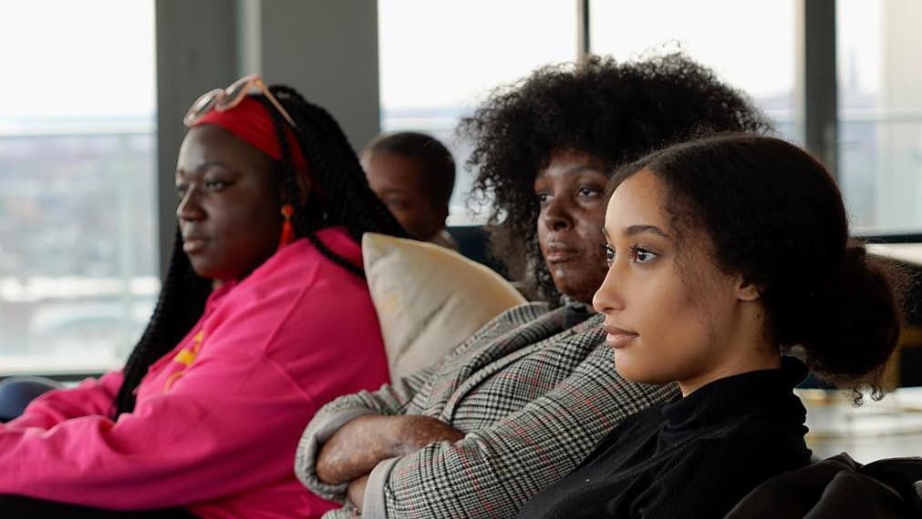 Three Black women in a meeting room at the Black Alliance for Just Immigration, an I-Belong grantee.