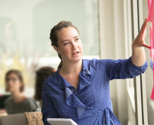 A Tides employee in the office gesturing towards a group of sticky notes on the window.