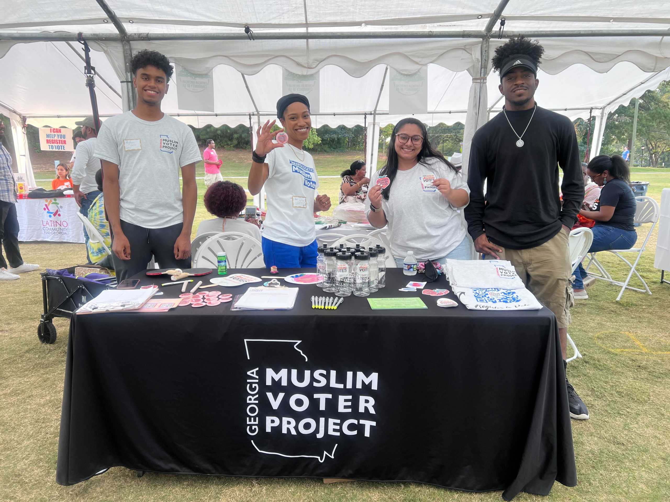 A group of four young BIPOC organizers tabling for the Georgia Muslim Voters Project.