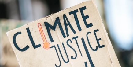 A light-skinned person holds up a sign that reads 