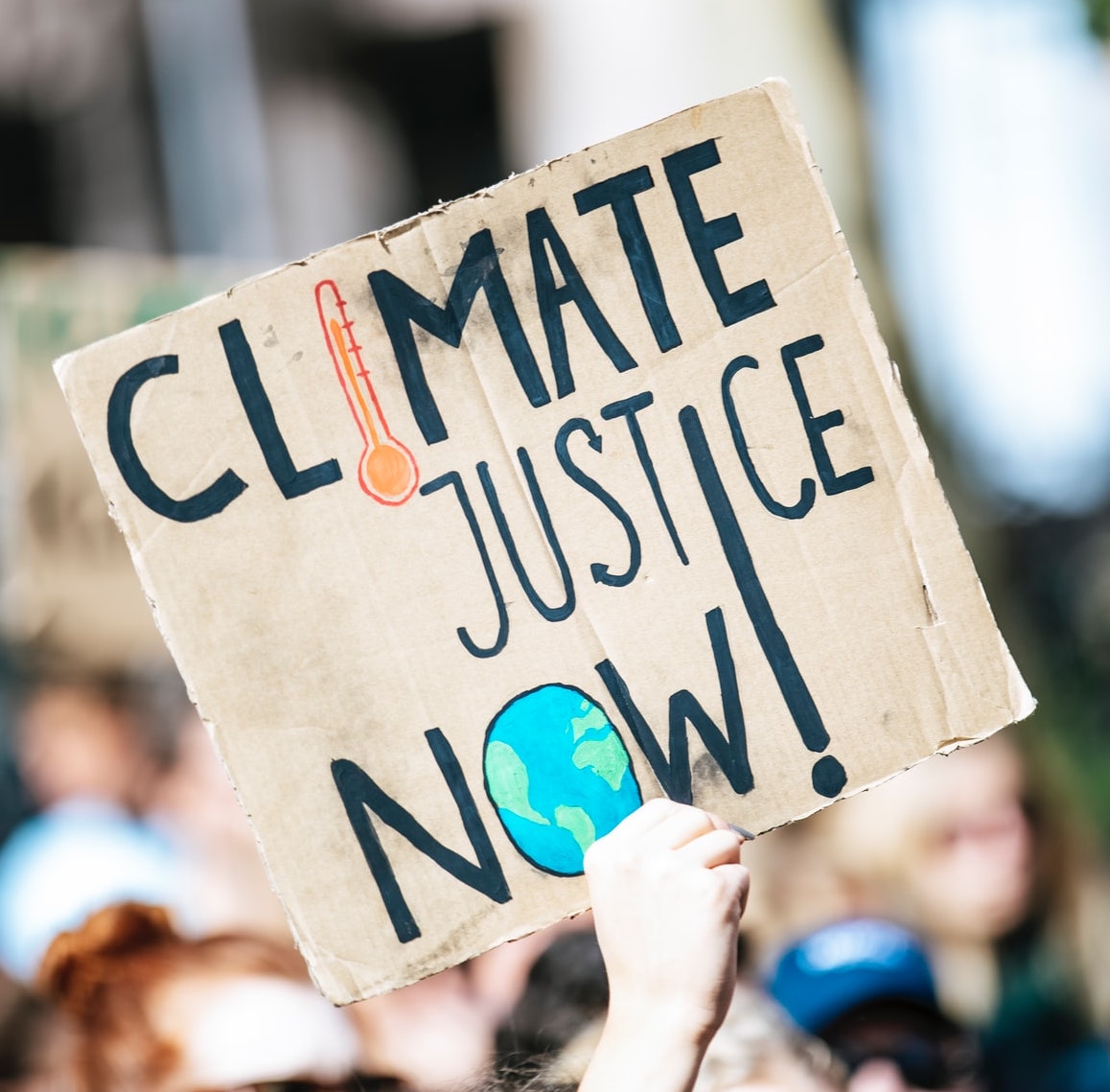 A light-skinned person holds up a sign that reads 