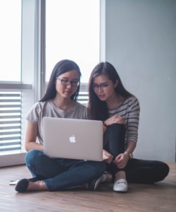 Two women looking at a laptop screen together.