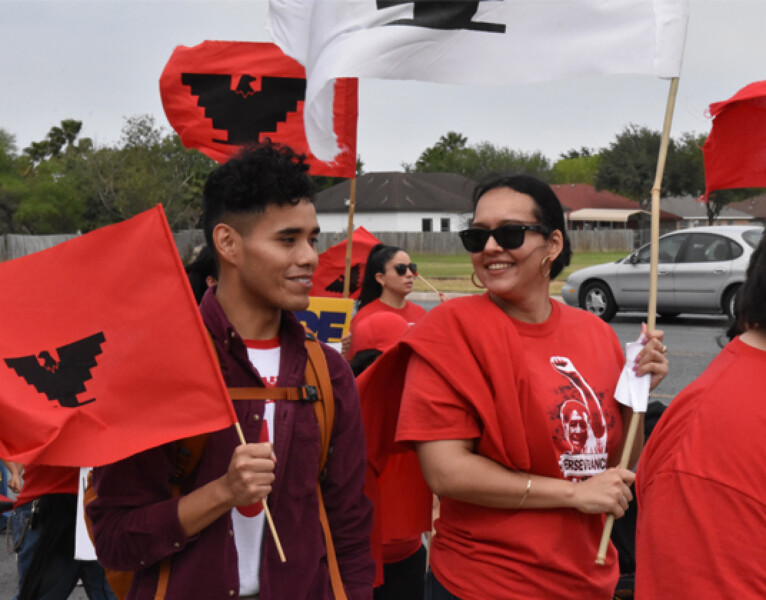 A group of Latine organizers marching with United Farm Workers flags which are red with a black Aztec eagle at the center. Photo credit: La Union del Pueblo Entero, a Tides Immigrants Belong Fund grantee