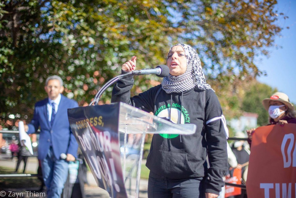 A young Muslim woman speaking at a climate justice protest. (Photo © Zayn Thiam)