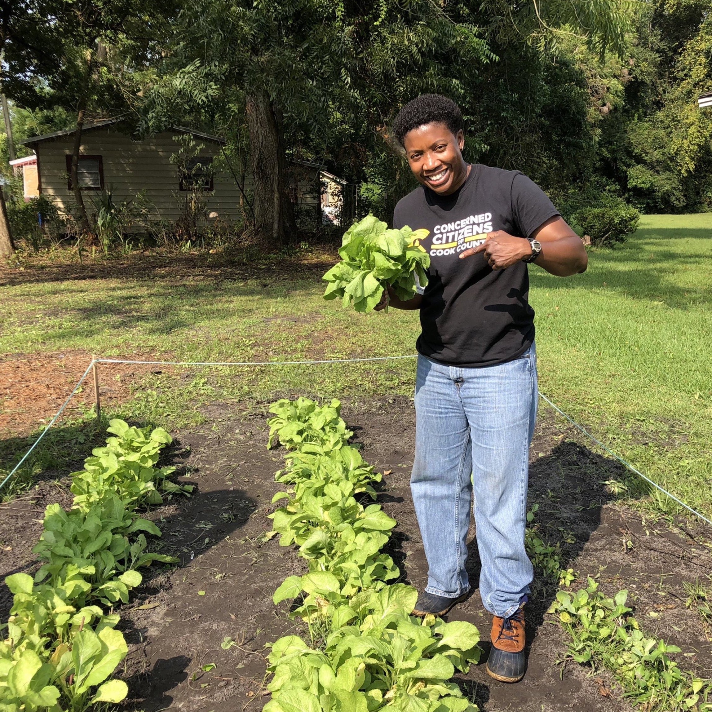 Dr. Treva Gear, founder of Concerned Citizens of Cook County (4C) holding up a head of lettuce in a community garden.
