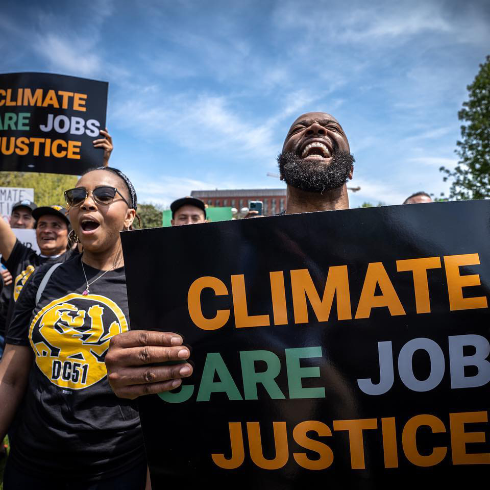 Protesters march holding signs that read ‘Climate Care Jobs Justice’ at a Fight For Our Future rally with the New Green Deal Network, a CAF at Tides.