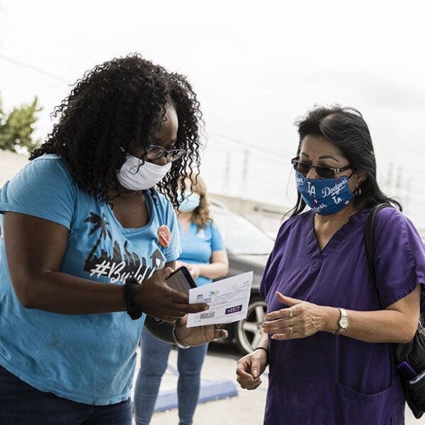 A volunteer helps a community member register to vote.