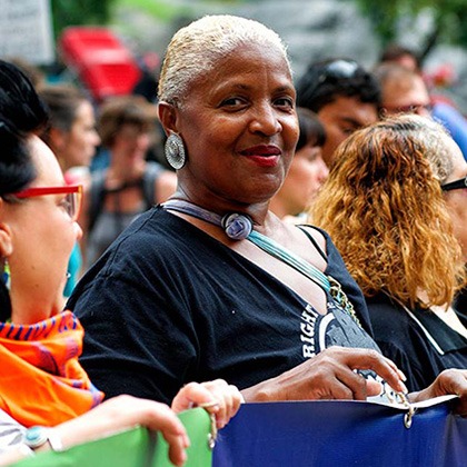 A protest with BIPOC women holding a large banner.