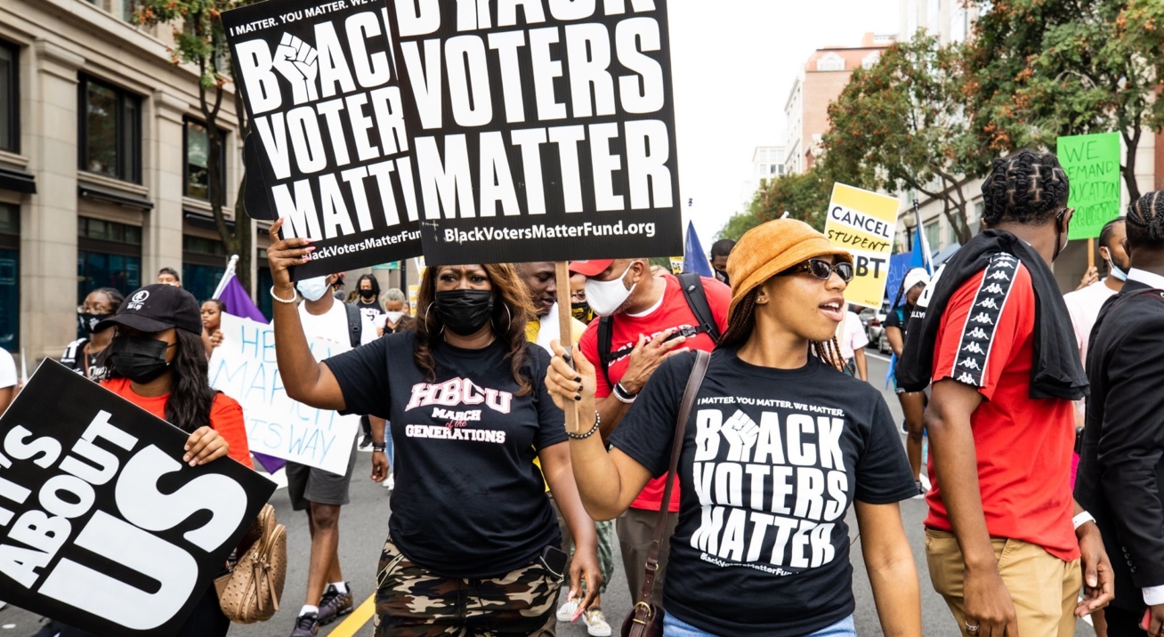 Black women leading a Black Voters Matter march and carrying signs. Photo credit: Black Voters Matter, a Tides Healthy Democracy Fund grantee