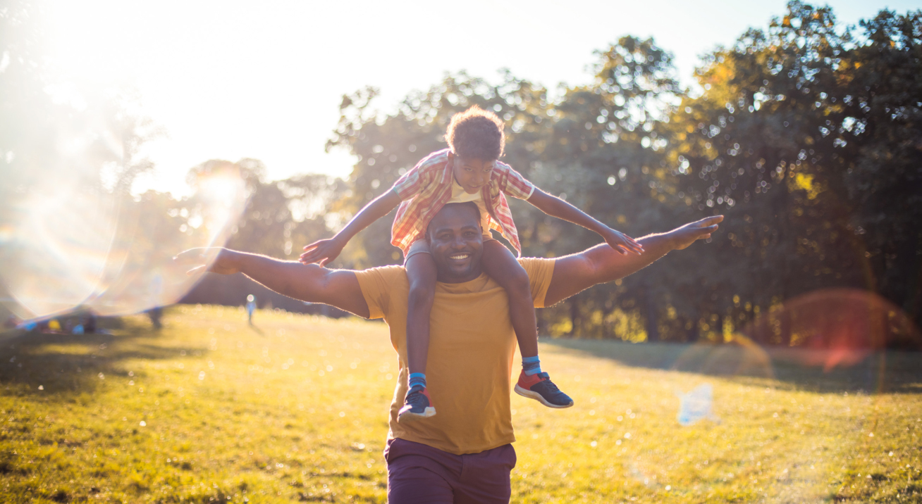 A Black father carrying his child on his shoulders. Source: iStock