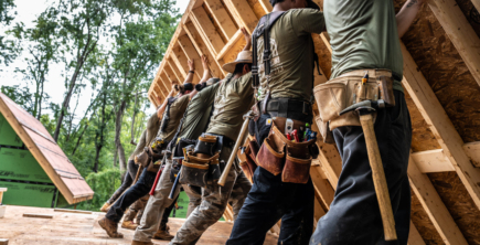 A row of builders lifting up a wall, rebuilding homes with BeLoved Asheville Hurricane Relief and Recovery.